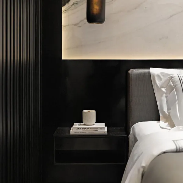 Dark bedroom with fluted panels, marble headboard wall and a bedside lamp